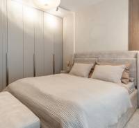 Világos hálószoba beépített szekrénnyel és ággyal egy háromszobás lakásban.