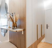 Előszoba tükörrel, szekrénnyel és dekorációval egy háromszobás lakásban, fa mintázatú padlóval.