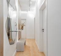 Világos előszoba tükörrel, paddal és fa dekorációjú padlóval egy háromszobás lakásban.