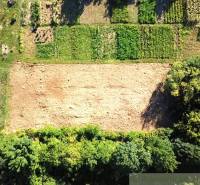 Lakóövezeti telkek Hosťován, rét a környező zöld parcellákkal, madártávlatból látható.