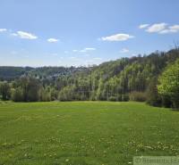 Tavaszi táj Krupina környékén, lakóterületek, zöld rétek és erdők a horizonton.