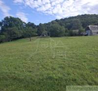 Rétek és épületek a Felsőtisovníkban, erdővel körülvéve.