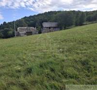 Füves domboldal épületekkel a háttérben, természettel körülvéve Felsőtisztviselőn, ideális lakóterületnek.