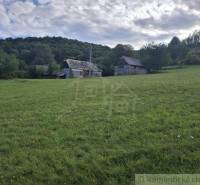 Zöld rét vidéki épülettel Felsőtisovníkban, alkalmas lakóterületnek.