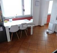 Ebédlő egy kétszobás lakásban fehér asztallal és barna padlóval.