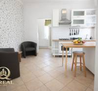 Konyha bárpulttal, gyümölcsökkel és székekkel egy egyszobás lakásban.