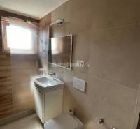 Fürdőszoba egy kétszobás lakásban mosdóval, zuhanyzóval és WC-vel.