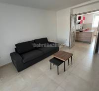 Nappali egy kétszobás lakásban fekete kanapéval és kis asztallal.