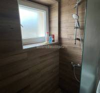 Zuhanykabin egy kétszobás lakásban fa dekor csempével és ablakkal.