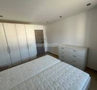 Hálószoba egy kétszobás lakásban fehér bútorokkal és fa dekorációjú padlóval.