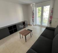 Nappali egy kétszobás lakásban fekete kanapéval és asztallal.