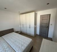 Hálószoba egy kétszobás lakásban ággyal és szekrénnyel, fa dekoros padlóval.