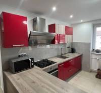 Konyha egy kétszobás lakásban beépített készülékekkel és fa mintázatú padlóval.