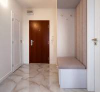 Előszoba egy 3 szobás lakásban csempével és kárpitozott paddal.