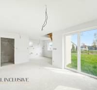 Egy berendezés nélküli házikó belső tere nagy ablakokkal és kilátással a kertre.