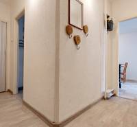 Folyosó egy kétszobás lakásban fehér falakkal és fa dekoros padlóval.