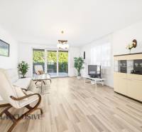 Világos nappali fa mintázatú padlóval, kanapé, fotel és televízió.