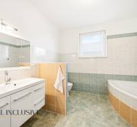 Fürdőszoba káddal, tükörrel és tárolóhellyel egy családi házban.