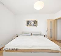 Hálószoba családi házban egyszerű bútorokkal és fa dekoros padlóval.