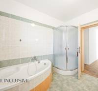 Családi ház fürdőszobája káddal, zuhanyzóval és csempézett falakkal.