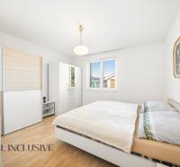 Hálószoba családi házban fa mintázatú padlóval, fehér bútorokkal és képpel.