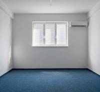 Irodák kék szőnyeggel, fehér falakkal és légkondicionálással.