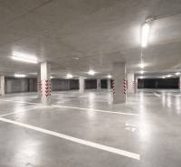 Tágas garázsok kijelölt parkolóhelyekkel, világos világítással, beton oszlopokkal.