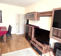 Nappali egy háromszobás lakásban, fa dekorációjú bútorokkal és padlóval.