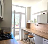 Konyha egy háromszobás lakásban bárpulttal, mikrohullámú sütővel és főzőlappal.