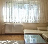 Nappali egy háromszobás lakásban fa dekoros padlóval és bőr kanapéval.