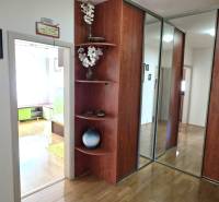 Folyosó egy 3 szobás lakásban fa dekor padlóval és beépített szekrénnyel.