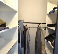 Beépített polcokkal és fa dekorációjú padlóval rendelkező gardrób egy háromszobás lakásban.