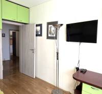 3 szobás lakás belső tere fa dekor padlóval, zöld tárolószekrényekkel.