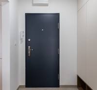 Előszoba egy háromszobás lakásban sötét ajtókkal és csempével.