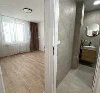 Szoba fa dekorációjú padlóval a fürdőszoba mellett egy kétszobás lakásban.