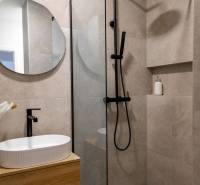 Fürdőszoba egy háromszobás lakásban mosdóval és zuhanyzóval fekete csapokkal.