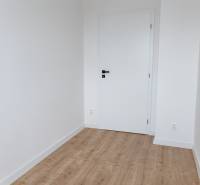 Szoba egy háromszobás lakásban fehér falakkal és fa dekorációjú padlóval.