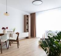 Nappali étkezőasztallal és fa dekorációjú padlóval egy háromszobás lakásban.