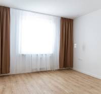 Szoba egy háromszobás lakásban barna függönyökkel és fa dekorációjú padlóval.