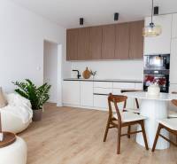 Nappali szoba konyhával egy háromszobás lakásban, fa dekoros padlóval.