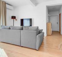 Világos nappali szoba fa hatású padlóval és szürke kanapéval egy kétszobás lakásban.