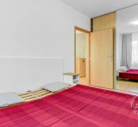 Hálószoba egy kétszobás lakásban nagy tükrös szekrénnyel és fa dekorációjú padlóval.