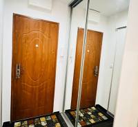 Folyosó egy 3 szobás lakásban ajtókkal, tükrös szekrénnyel és színes szőnyeggel.