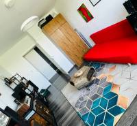 Nappali egy háromszobás lakásban, piros kanapéval és fa dekoros padlóval.