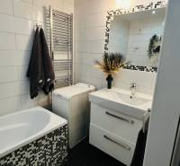 Elegáns fürdőszoba csempékkel, mosdóval és káddal, a háromszobás lakás része.