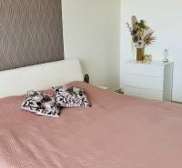 Hálószoba egy háromszobás lakásban ággyal, dekoratív párnákkal és díszes tapétával.