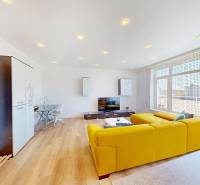 Nappali egy kétszobás lakásban fa mintázatú padlóval és sárga kanapéval.