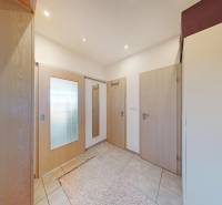 Két szobás lakás előszobája járólappal, világos ajtókkal és tükörrel.