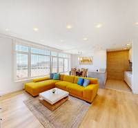 Világos nappali kanapéval, étkezőasztallal és fa mintázatú padlóval egy kétszobás lakásban.