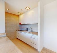 Konyha egy kétszobás lakásban fehér szekrényekkel és fa mintázatú padlóval.